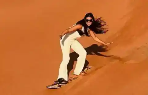 Voyageuse en sandboard sur une dune