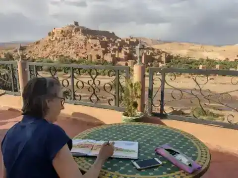 Voyageuse dessinant face à une kasbah — Responsible Travel